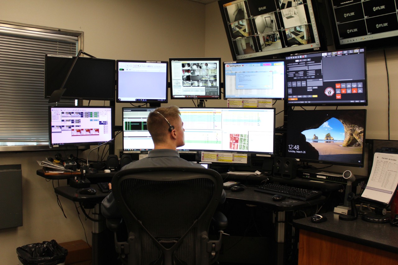 An emergency communications dispatcher sits in front of multiple computer screens.