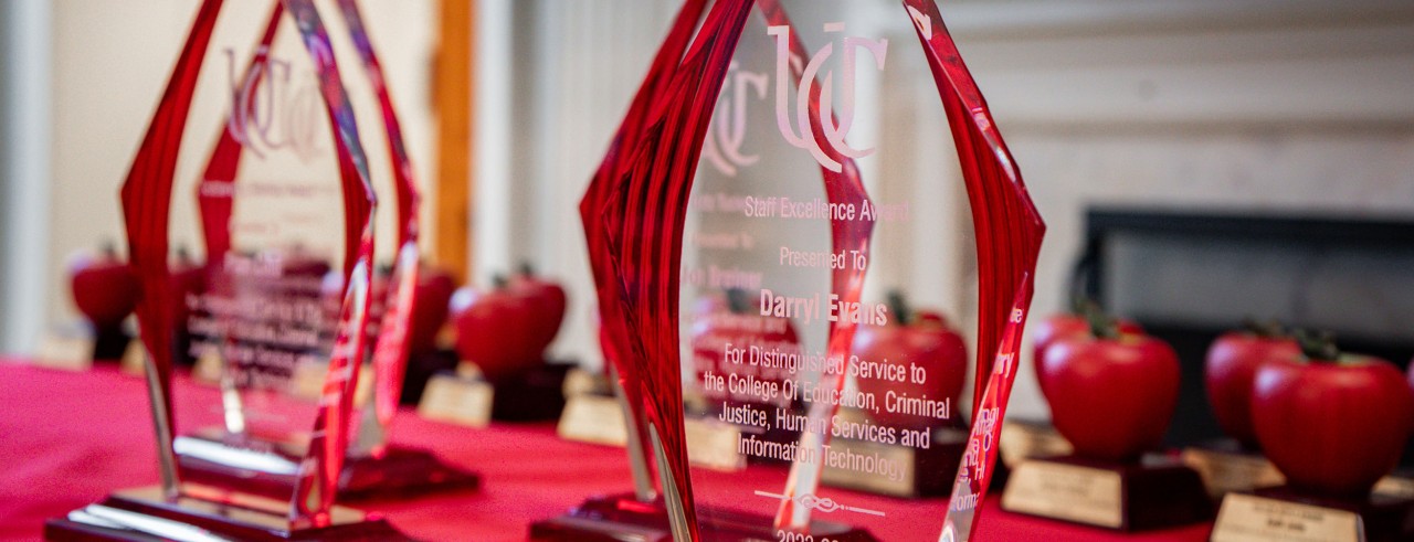 Glass and apple-shaped awards sit on a table with a red table cloth.