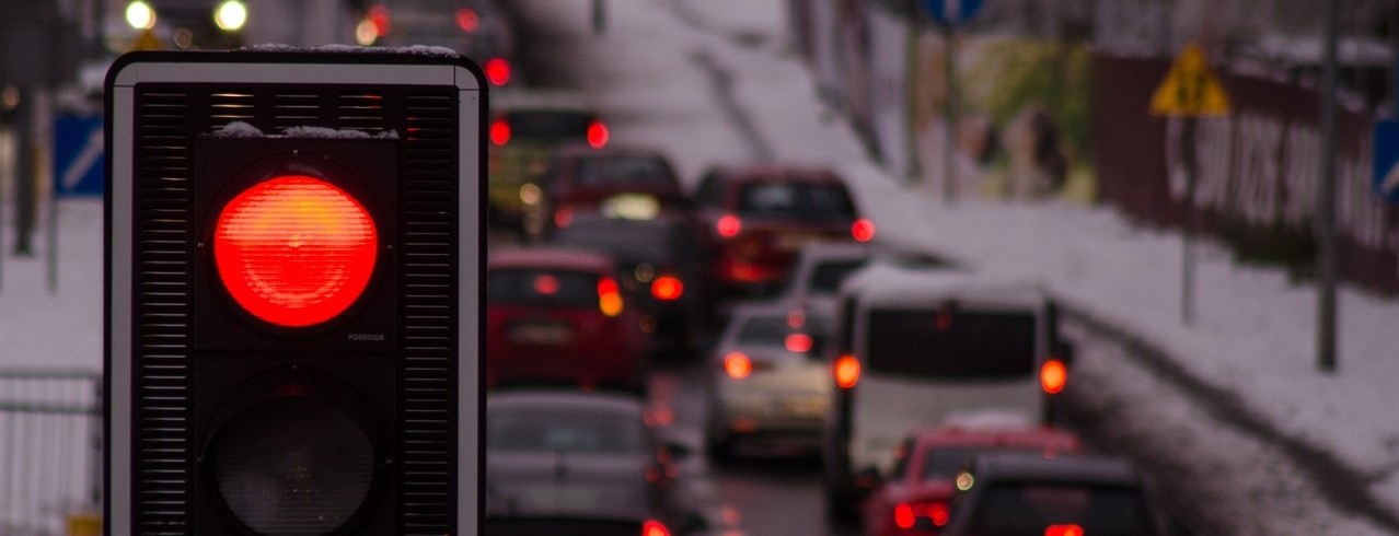 Red traffic light in front of line of cars