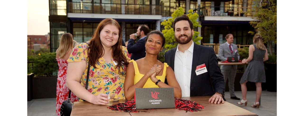 alumni smiling while standing at a table