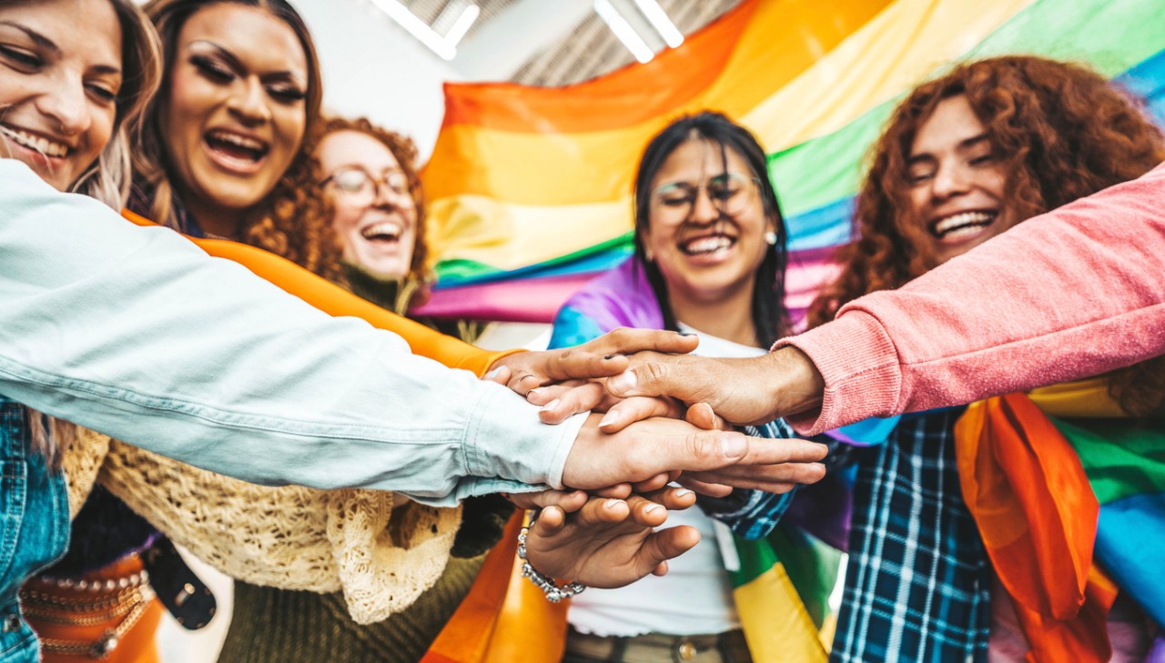 LGBTQ group of people stacking hands outside