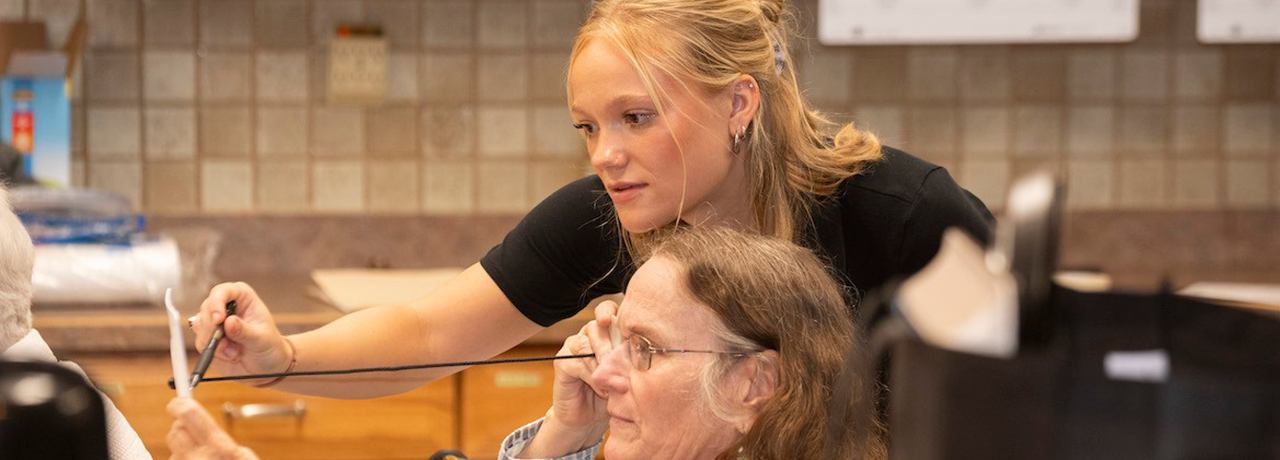 Occupational therapy student Anne Reed assists senior during Successful Aging in the Geriatric Experience (SAGE) 2023.