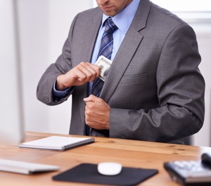 Cropped shot of a businessman putting money into his blazer pocket