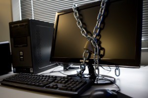 Computer, keyboard and monitor displayed with chain and lock around monitor for security.