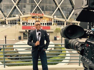 Sportscaster Lewis Johnson reports in front of a camera.