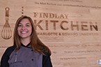 Chef Lindsey standing in front of the Findly Kitchen sign 