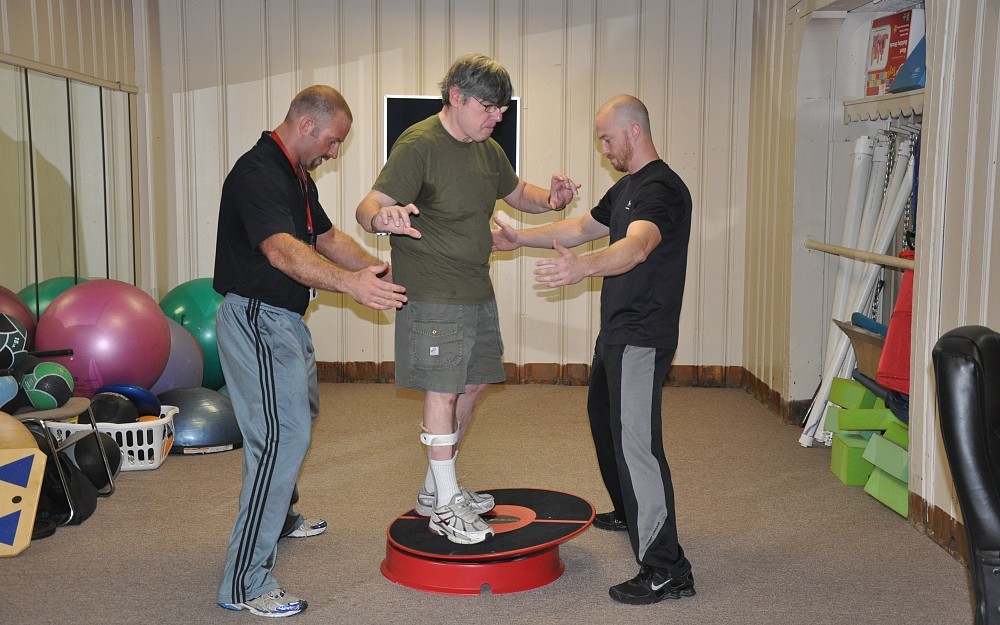 Brian Terpstra, PhD (left), and Tim Kemme, right, work with an Exercise Initiative participant using a Core-Tex platform. 